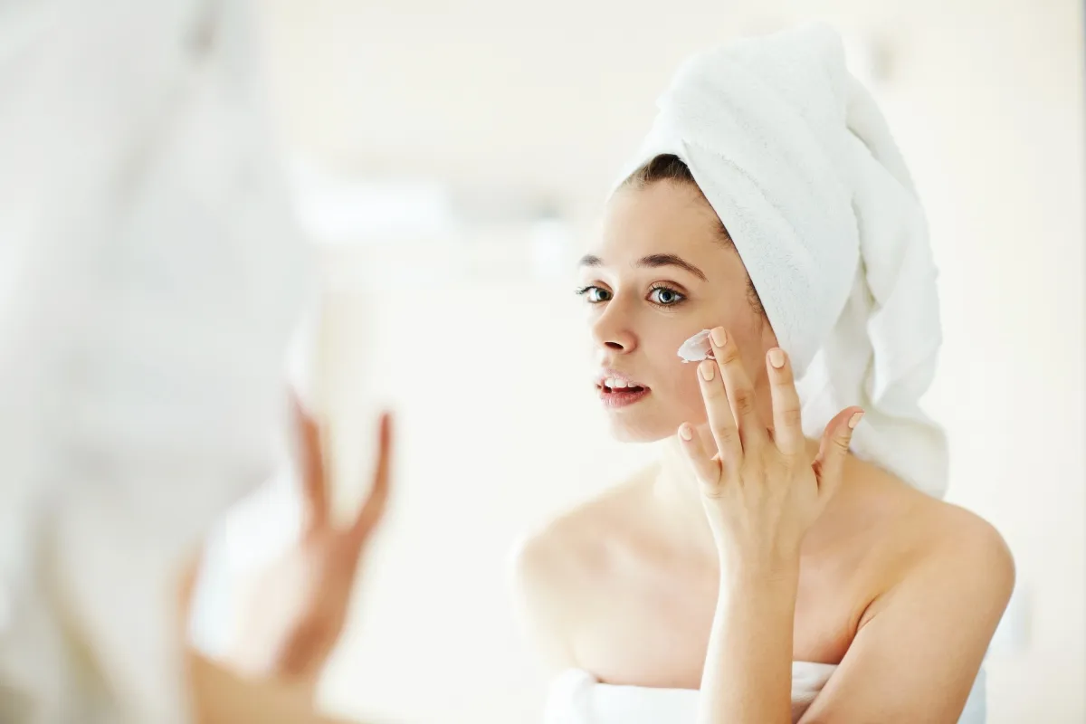 woman-in-towel-putting-on-face-cream-getty-1019 Chăm sóc da đúng cách giúp duy trì vẻ tươi trẻ trong những ngày hè oi bức